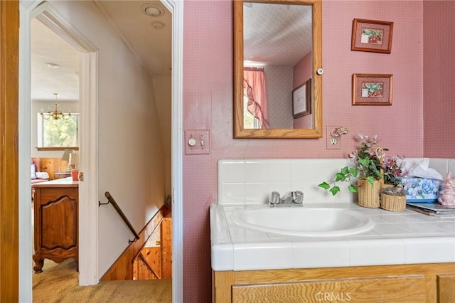 bathroom featuring a notable chandelier, wallpapered walls, and vanity