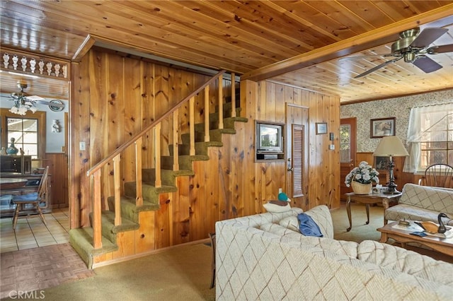 carpeted living area with stairs, wood ceiling, wood walls, and ceiling fan