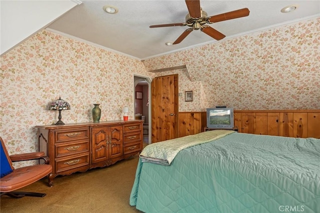 bedroom featuring a wainscoted wall, light carpet, ornamental molding, a textured ceiling, and wallpapered walls