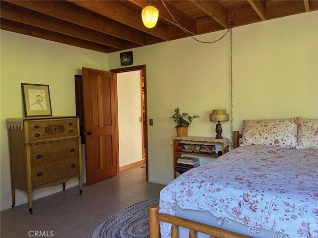 bedroom with dark tile patterned flooring and beamed ceiling