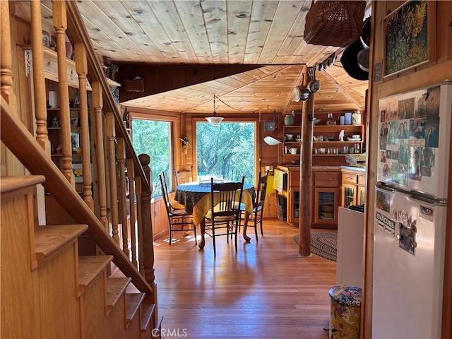 dining room with wooden walls, wooden ceiling, wood-type flooring, and stairs