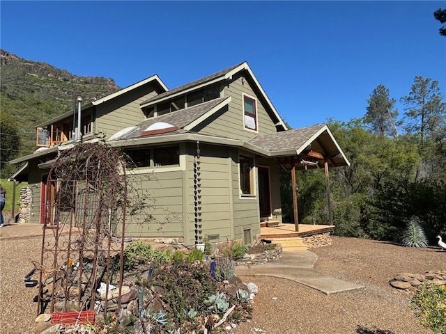 view of side of home with roof with shingles and a mountain view