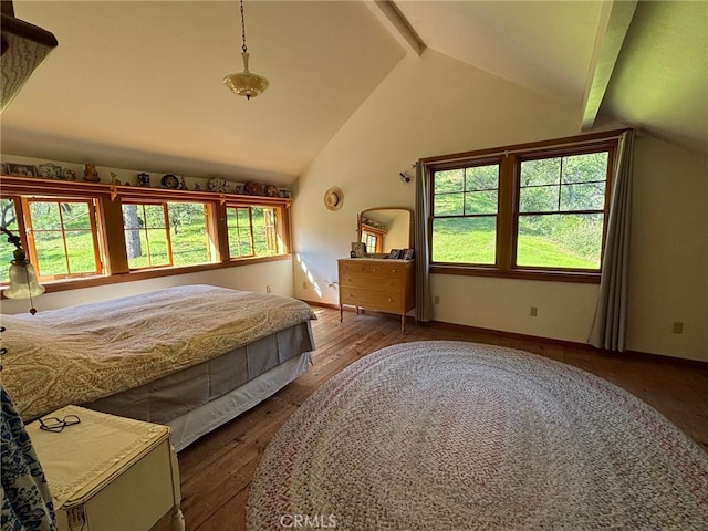 bedroom with baseboards, lofted ceiling with beams, and wood finished floors