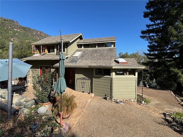view of front of property featuring a shingled roof, a patio area, and a mountain view