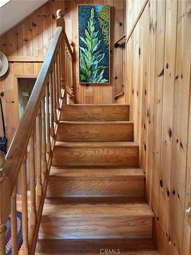stairway featuring wood walls