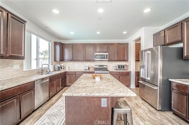 148 Mesquite Ct, Calimesa, CA 92320 - kitchen featuring a kitchen breakfast bar, a kitchen island, a sink, light stone countertops, and appliances with stainless steel finishes
