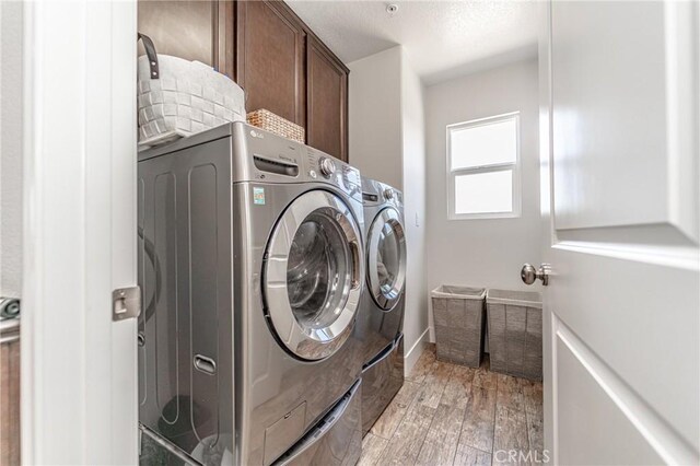 148 Mesquite Ct, Calimesa, CA 92320 - clothes washing area featuring baseboards, a textured ceiling, light wood-style floors, cabinet space, and washing machine and dryer
