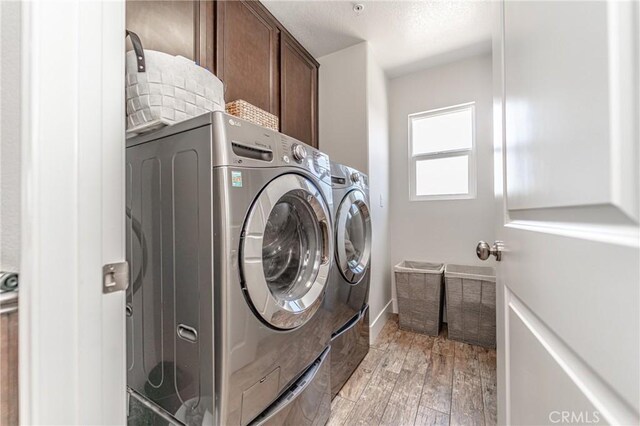 148 Mesquite Ct, Calimesa, CA 92320 - washroom featuring cabinet space, washer and clothes dryer, light wood-type flooring, and a textured ceiling