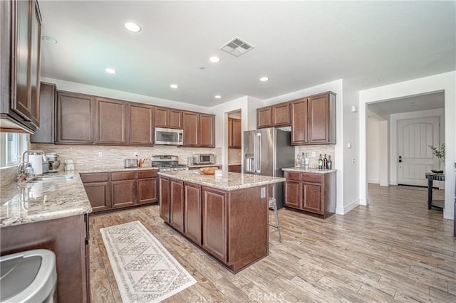 148 Mesquite Ct, Calimesa, CA 92320 - kitchen with appliances with stainless steel finishes, a center island, backsplash, light stone countertops, and recessed lighting