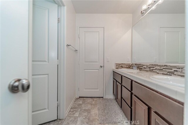 148 Mesquite Ct, Calimesa, CA 92320 - bathroom featuring double vanity, tasteful backsplash, baseboards, and a sink