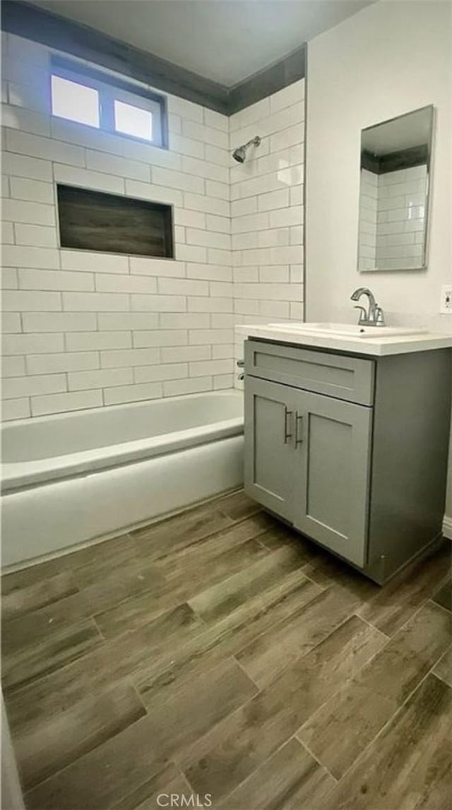 bathroom with shower / washtub combination, wood finished floors, and vanity