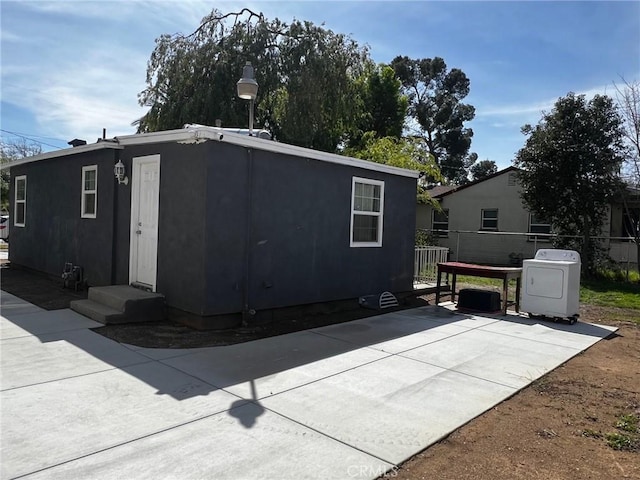 exterior space with entry steps, washer / clothes dryer, a patio area, and stucco siding