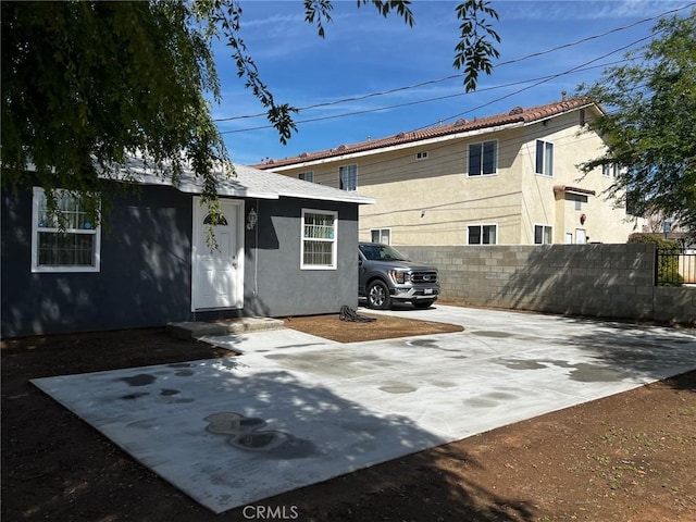 rear view of property with stucco siding, a patio, and fence