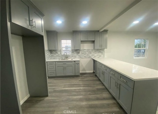 kitchen with tasteful backsplash, gray cabinets, and a sink