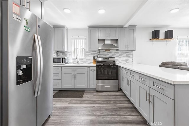 24412 Eucalyptus Ave, Moreno Valley, CA 92553 - kitchen with stainless steel appliances, wall chimney exhaust hood, gray cabinets, a peninsula, and plenty of natural light