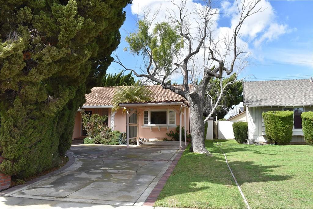 view of front of property with stucco siding, a tile roof, concrete driveway, a front yard, and an attached carport