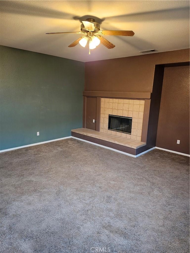 unfurnished living room featuring ceiling fan, carpet, visible vents, a tile fireplace, and baseboards