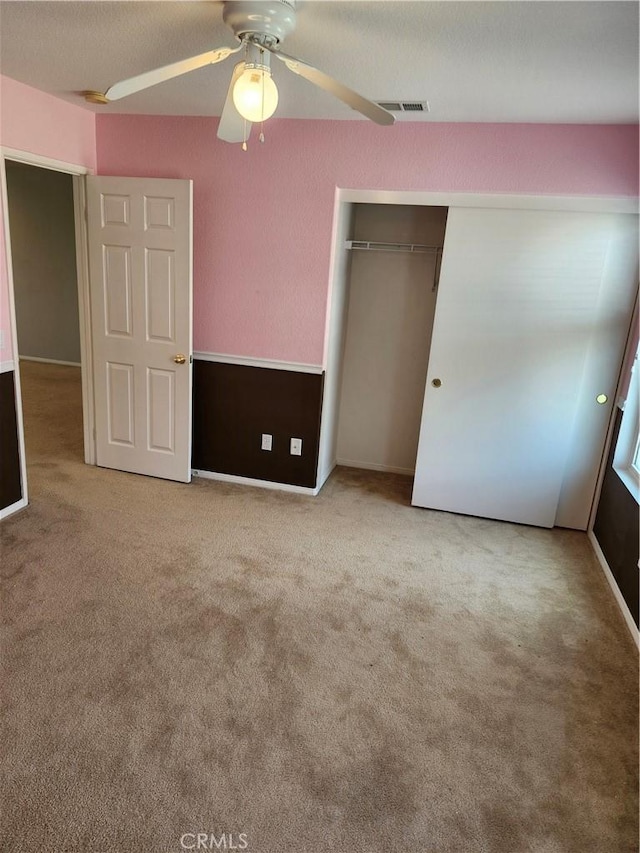 unfurnished bedroom featuring a closet, ceiling fan, visible vents, and carpet floors