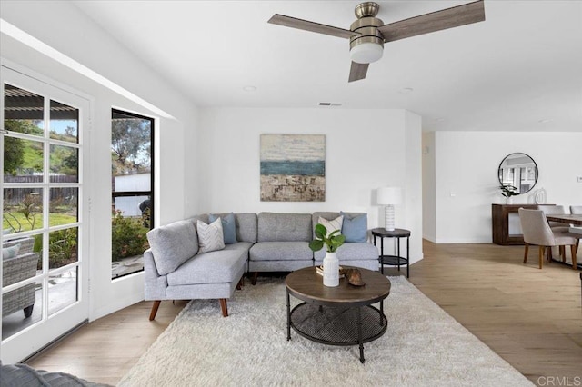 living area featuring wood finished floors, visible vents, and ceiling fan