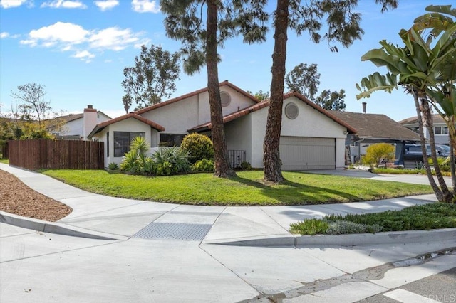 view of front of home with stucco siding, a front lawn, driveway, fence, and a garage