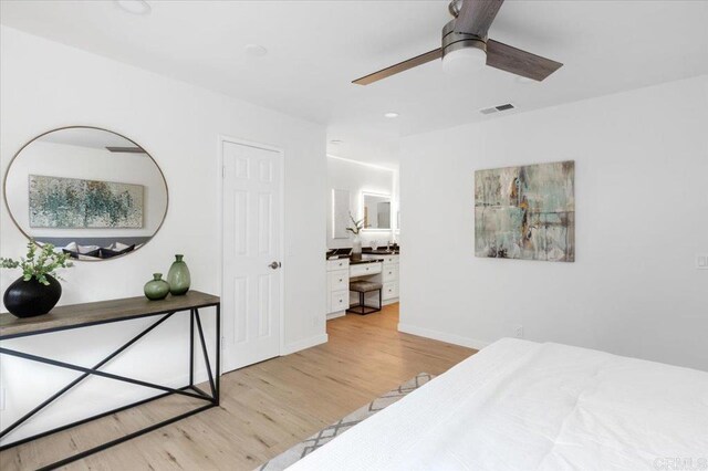 bedroom featuring visible vents, baseboards, wood finished floors, ensuite bath, and a ceiling fan