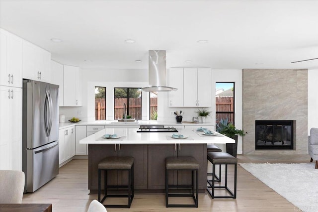 kitchen featuring a healthy amount of sunlight, a center island, island exhaust hood, freestanding refrigerator, and a sink