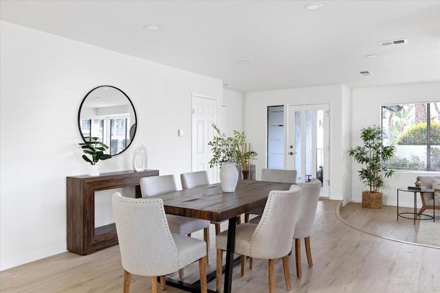 dining area with light wood-style floors, visible vents, and baseboards