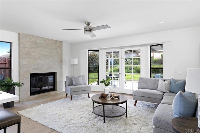 living room featuring ceiling fan, a healthy amount of sunlight, light wood-type flooring, and a premium fireplace