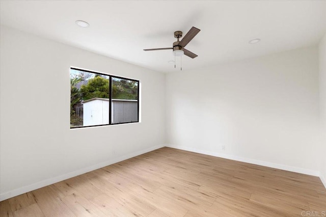 empty room featuring baseboards, ceiling fan, and light wood finished floors