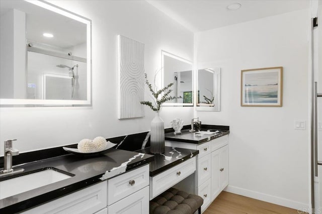 full bath featuring baseboards, vanity, walk in shower, and wood finished floors