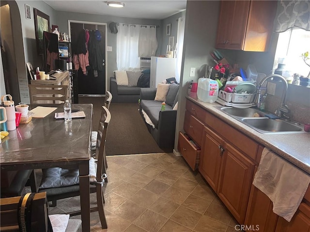 kitchen with a sink, brown cabinets, dishwasher, and light countertops