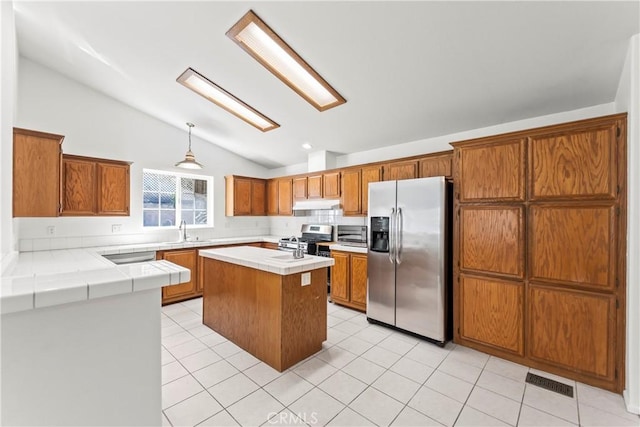 kitchen featuring tile counters, visible vents, lofted ceiling, and stainless steel appliances