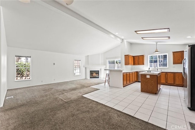 kitchen featuring stainless steel fridge with ice dispenser, open floor plan, light colored carpet, lofted ceiling with beams, and brown cabinetry