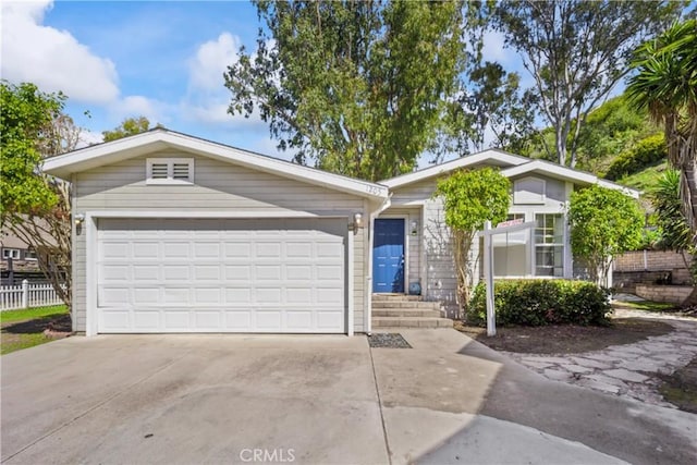 view of front of property featuring an attached garage, concrete driveway, and fence