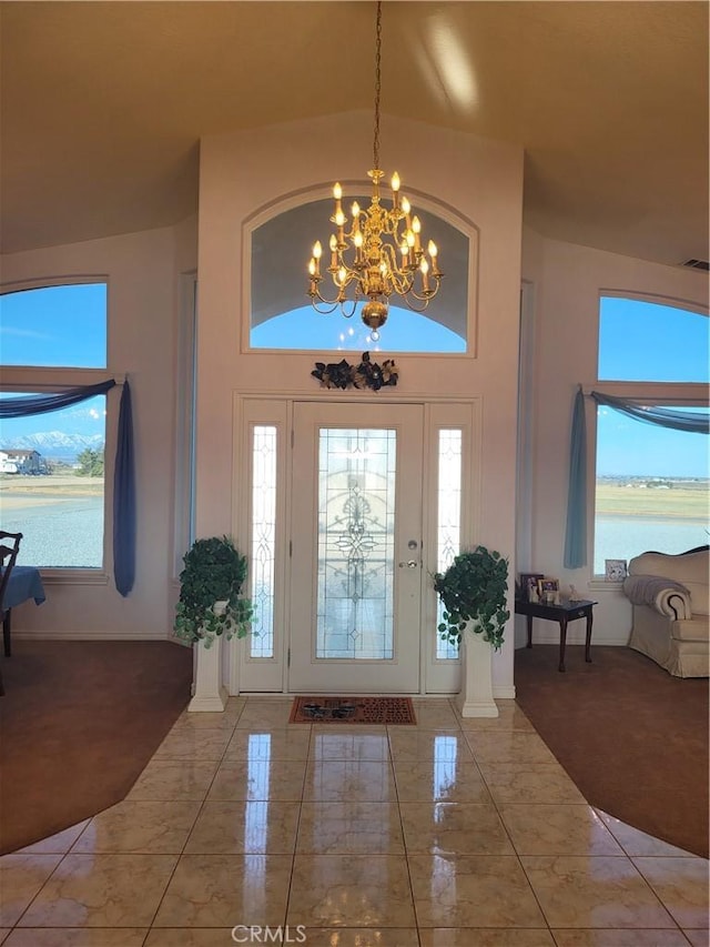 entrance foyer with high vaulted ceiling, marble finish floor, a water view, and a chandelier