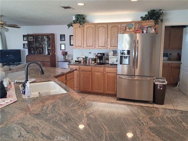 kitchen with a sink, a textured ceiling, stainless steel fridge with ice dispenser, light tile patterned floors, and ceiling fan