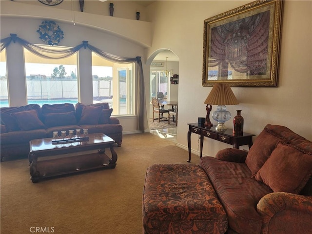 carpeted living room with baseboards and arched walkways