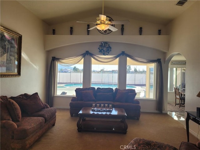 carpeted living room with visible vents, baseboards, ceiling fan, vaulted ceiling, and arched walkways