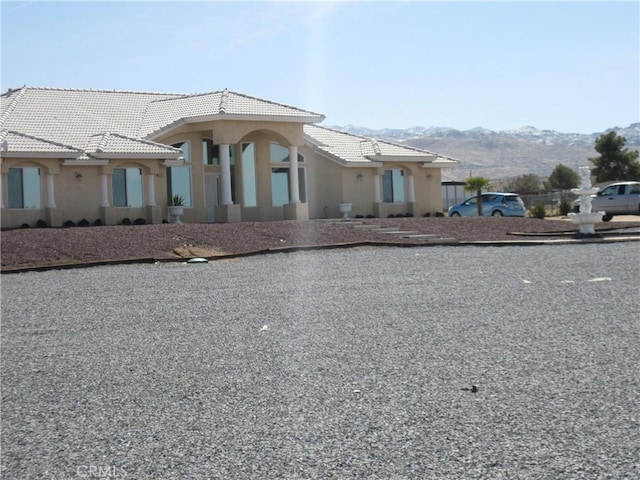 view of front of home with a tile roof, a mountain view, and stucco siding