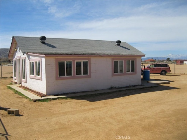 view of side of property with fence, concrete block siding, and a shingled roof