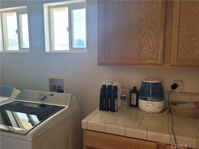 clothes washing area featuring a wealth of natural light, cabinet space, and separate washer and dryer