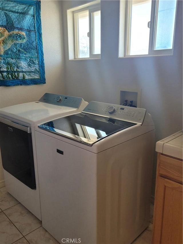 washroom with cabinet space, washing machine and dryer, and a healthy amount of sunlight