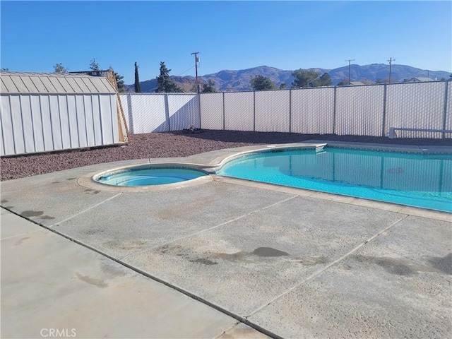 view of swimming pool featuring a patio, a fenced in pool, an in ground hot tub, a fenced backyard, and a mountain view