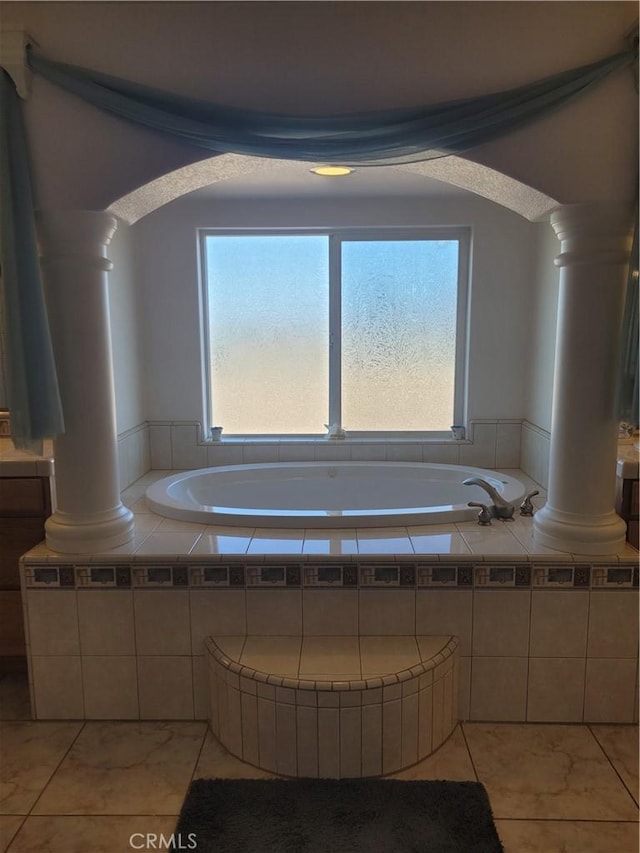 full bathroom featuring a garden tub, decorative columns, and tile patterned floors