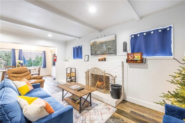 living room featuring a fireplace, beam ceiling, wood finished floors, and baseboards