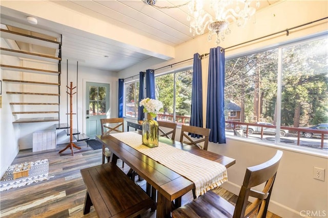 dining area featuring a notable chandelier, beamed ceiling, and wood finished floors