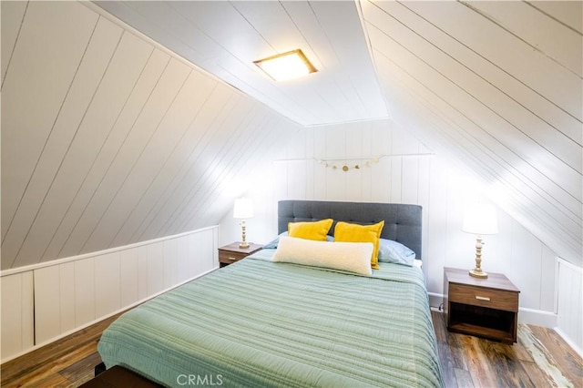 bedroom with wooden walls, wood finished floors, and vaulted ceiling