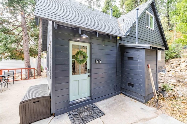 doorway to property featuring roof with shingles