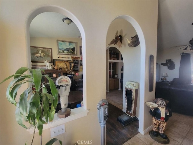 corridor featuring arched walkways and tile patterned floors