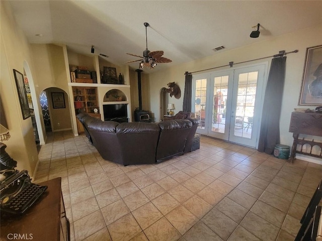 living room featuring french doors, light tile patterned flooring, built in shelves, lofted ceiling, and a ceiling fan